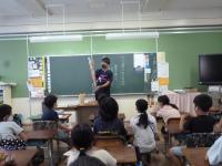 先生が、4年生の子どもたちに東京オリンピックの聖火トーチを見せています。