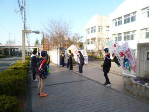 中学校の門で募金活動をする小学生